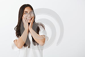 So sweet receiving compliments. Portrait of positive happy good-looking female coworker in glasses and white t-shirt