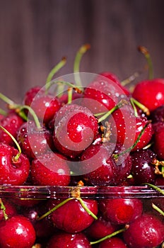 Sweet red cherries in glass bowl on dark wooden backgound with copy space. Summer and harvest concept. Vegan, vegetarian