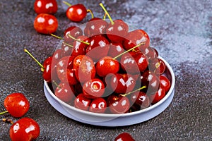 Sweet red cherries in a plate on dark background