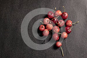 Sweet red cherries scattered on black background. Top view. Fruit Background