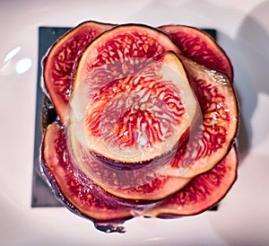 Sweet red figs slices on white dish close up