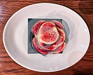 Sweet red figs slices on white dish close up