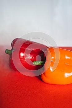 SWEET RED AND ORANGE PEPPERS ON A RED BACKGROUND