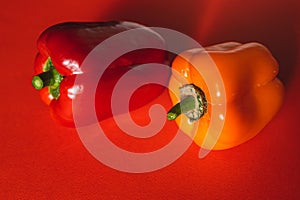 SWEET RED AND ORANGE PEPPERS ON A RED BACKGROUND