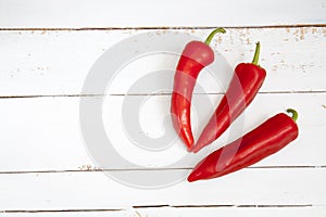 Sweet red pepper kapi, three peppers on white wooden table