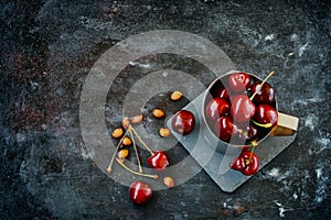 Sweet ripe cherries in metal mug on old black scratched background