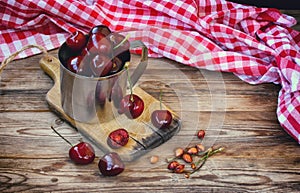 Sweet ripe cherries in metal mug on old wooden table