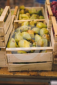 Sweet ripe pears in wooden box. Seasonal fruit department in supermarket, food store. Shop local, farm products, vegan, vegetarian