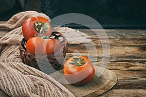 Sweet ripe persimmon in wicker bowl and cloth napkin