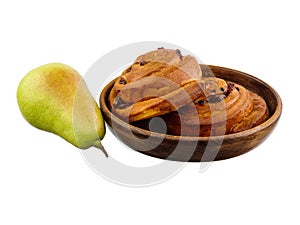 Sweet roll with cinnamon on a plate, next pear isolated on a white background