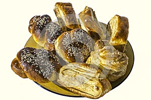 Sweet rolls covered with sesame seeds with Gata and Eclair on a yellow ceramic plate on white background