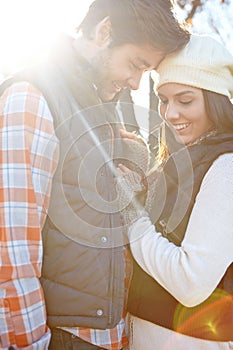 Sweet romance on an autumn day. A loving young couple being affectionate while standing together in the outdoors.