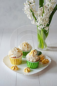 Sweet romantic breakfast with bouquet fresh spring flowers, defocused. vanilla capcake dessert wooden background, top