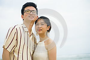 Sweet and romantic lifestyle portrait of young happy Asian Chinese couple in love enjoying holiday on beautiful beach walking