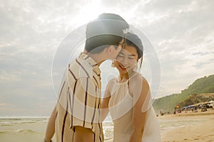 Sweet and romantic lifestyle portrait of young happy Asian Korean couple in love enjoying holiday on beautiful beach walking