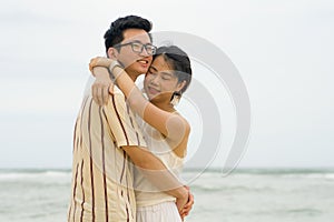 Sweet and romantic lifestyle portrait of young happy Asian Korean couple in love enjoying holiday on beautiful beach walking