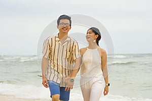 Sweet and romantic lifestyle portrait of young happy Asian Korean couple in love enjoying holiday on beautiful beach walking