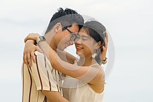 Sweet and romantic lifestyle portrait of young happy Asian Korean couple in love enjoying holiday on beautiful beach walking