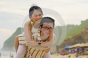 Sweet and romantic lifestyle portrait of young happy Asian Korean couple in love enjoying holiday on beautiful beach walking