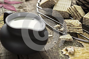 Sweet russian artek waffles on wooden background, with a pot of milk. Traditional sweets and dessert