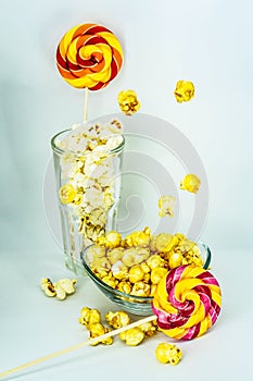 Sweet and salty popcorn with candy on a stick on a white background.