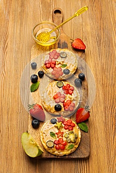 Sweet sandwiches peanut butter with fruits, berries with honey on a wooden board, top view.