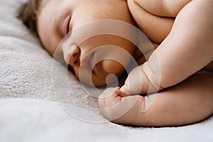 Sweet sleeping newborn baby fists in bed