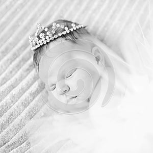 Sweet sleeping newborn baby girl with crown jewelry sleeping ona grey blanket