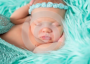 Sweet sleeping newborn girl with flowers on headband