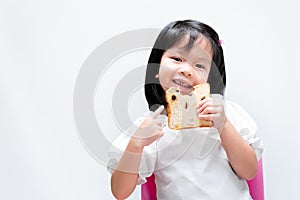 A sweet smiling little girl, a child holding a raisin bread, kid pointing a finger at the bread, children enjoying eating a slice