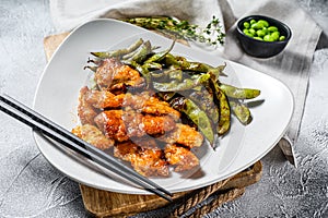 Sweet and sour chicken with beans edamame on a plate. Chinese dish. White background. Top view
