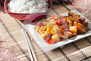 Sweet and sour chicken with bell pepper and pineapple. White rice on background