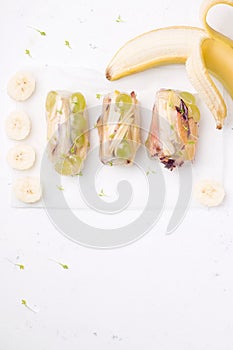 sweet spring rolls of fruit next to a fresh, banana