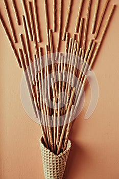 Sweet straw in waffle cone on beige background, snack, close up concept photography and content for food blog