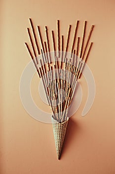 Sweet straw in waffle cone on beige background, snack, concept flat lay photography and content for food blog