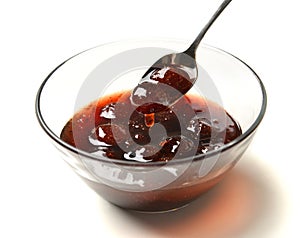 Sweet strawberry jam in the transparent glass bowl with tea spoon