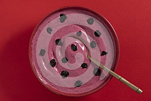 Sweet summer cherry soup in a plate on a red background, closeup, top view. Hungarian cold red cherry soup with yogurt or cream