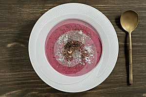 Sweet summer cherry soup in a white plate on a wooden background, closeup, top view. Hungarian cold red cherry soup with yogurt or