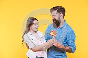 Sweet surprise. Bearded man give lollipop to surprised child. Sweet tooth family yellow background. Sweetshop and