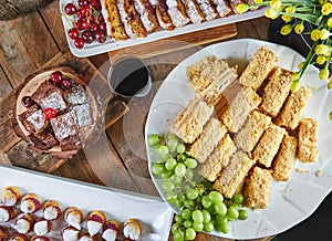 Sweet table with a selection of cakes and pastries with grapes and red wine