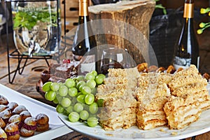 Sweet table with a selection of cakes and pastries with grapes and red wine