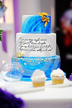 Sweet table set with blue cake and cupcakes on wedding party