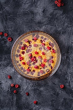 Sweet tasty pie with jellied and fresh raspberry fruits in baking dish, dark stone concrete background