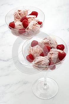 Sweet temptation and refreshing summer treat concept with vibrant pink raspberries soft ice cream in glass cups and raw