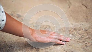 Sweet tender female hand gently runs her fingers along ancient stone rock, stroking ancient nature, light touch to