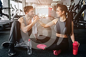 Sweet and tender picture of two beloved people sitting on the floor in the gym close to each other. They look lovely and