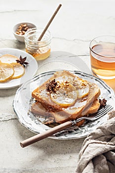 Sweet toast with cream cheese, caramelized pear, nuts and honey with cup of tea for breakfast on textured background