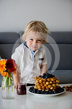 Sweet toddler child, boy, eating bubble waffles with fruits at home for breakfast