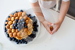 Sweet toddler child, boy, eating bubble waffles with fruits at home for breakfast