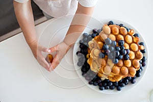 Sweet toddler child, boy, eating bubble waffles with fruits at home for breakfast